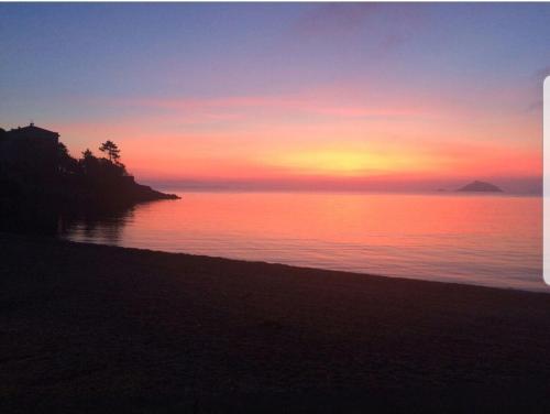 a sunset over the water with a beach and the ocean at Cavo Beach 1 in Cavo