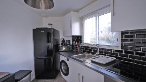 La cuisine est équipée d'un évier et d'un réfrigérateur noir. dans l'établissement Villa Saquèdes, à Sainte-Maxime