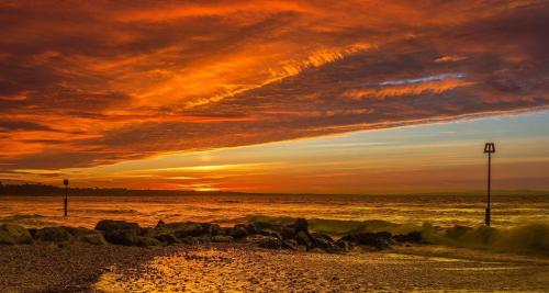 a sunset over the ocean with rocks on the beach at Bub Lane Cottage in Christchurch