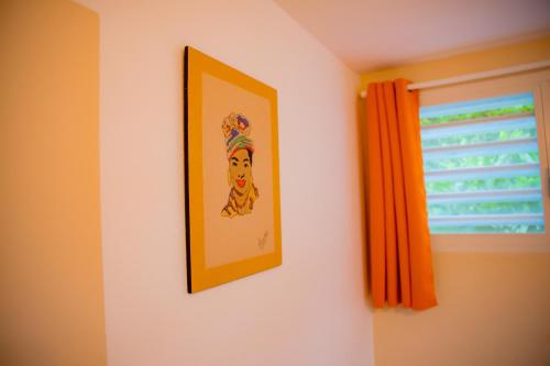 a picture hanging on a wall next to a window at Villas Ixora in Sainte-Anne