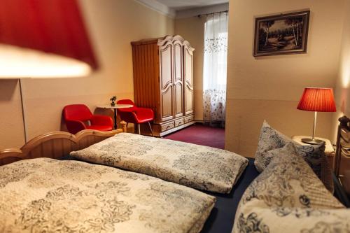 a hotel room with two beds and red chairs at Hotel und Restaurant Peking in Riesa