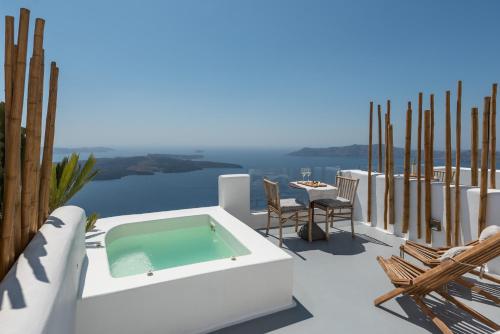 a terrace with a swimming pool and a table and chairs at Cocoon Suites in Imerovigli