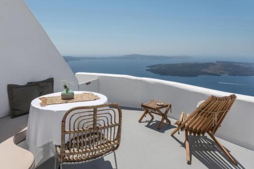 a table and chairs on a balcony with a view at Cocoon Suites in Imerovigli