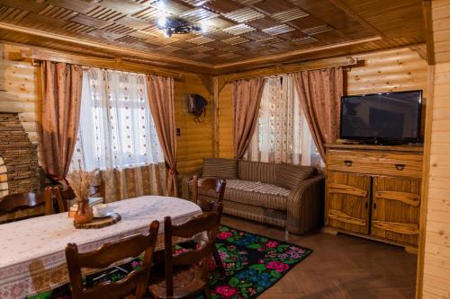 a living room with a table and a tv and a couch at Karpaty Migovo in Migovo