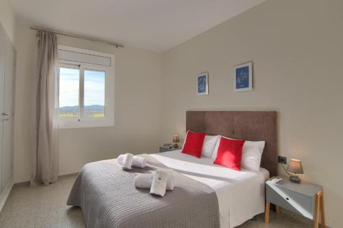 Un dormitorio con una cama con almohadas rojas y una ventana en Alquiler apartamento en Pals, en Pals