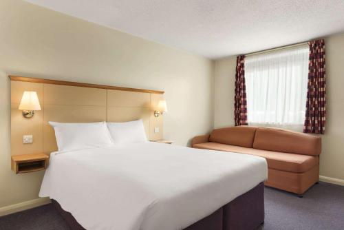 una habitación de hotel con una cama grande y una silla en Days Inn Cannock - Norton Canes en Cannock