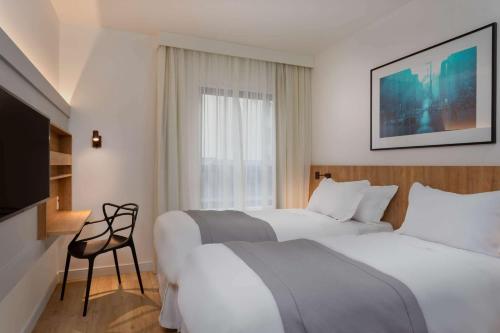 a hotel room with two beds and a tv at TRYP by Wyndham Sao Paulo Paulista Paraiso in São Paulo