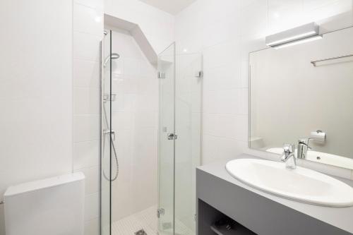 une salle de bain blanche avec un lavabo et une douche dans l'établissement Georgia by Cocoonr, à Rennes