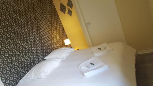 a bedroom with a bed with white sheets and towels at Hôtel Restaurant le clos de l 'Ancien Pressoir in Commes