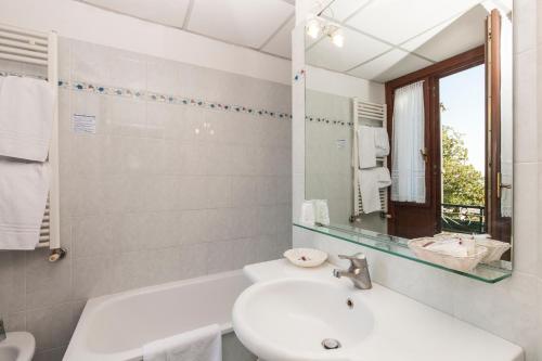 Baño blanco con lavabo y espejo en Hotel Riviera Venezia Lido, en Lido de Venecia