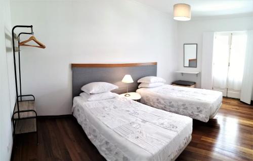 2 Betten in einem Zimmer mit weißen Wänden und Holzböden in der Unterkunft Casa Arcanjo in Lagoa