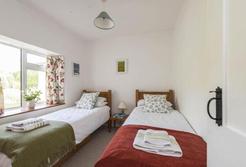 a bedroom with two beds and a window at Jurassic Cottage in Portesham