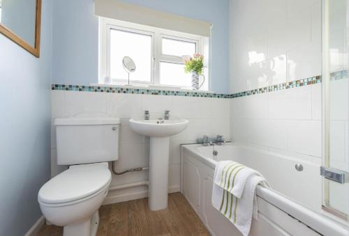 a bathroom with a toilet and a sink and a tub at Jurassic Cottage in Portesham