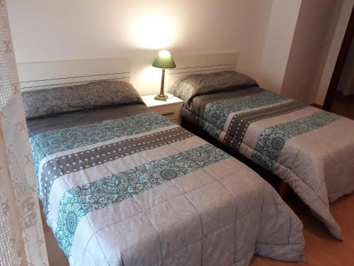 Habitación con 2 camas y una lámpara en una mesa. en Apartamento Parque de Quevedo en León
