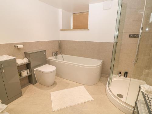 a bathroom with a tub and a toilet and a shower at Upper House Barn Saddleworth in Oldham