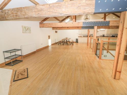a large room with wooden floors and wooden beams at Upper House Barn Saddleworth in Oldham