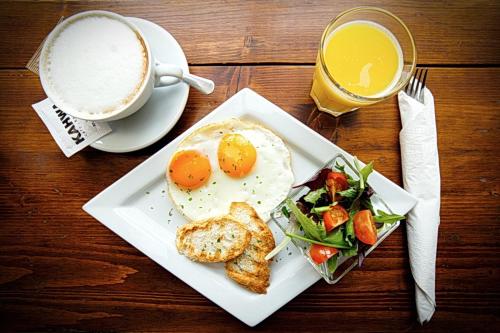 einen Tisch mit einem Frühstücksteller und einer Tasse Kaffee in der Unterkunft Kahwa Central Apartments in Budapest