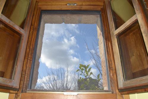 a window in a wooden door with the sky at Notti Etrusche a Sovana in Sovana