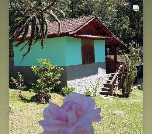 une maison avec une fleur rose devant elle dans l'établissement Chalés Aguá Cristalina, à Visconde de Mauá