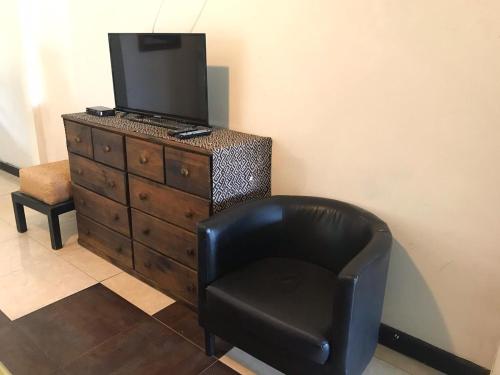 a black chair sitting next to a dresser with a television on it at Posada Nativa Trinsan Centro in San Andrés