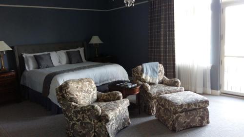 a bedroom with a bed and two chairs at The Bruce Hotel in Stratford