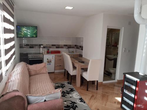 ein Wohnzimmer mit einem Sofa und einem Tisch sowie eine Küche in der Unterkunft Vučeljić rooms in Andrijevica