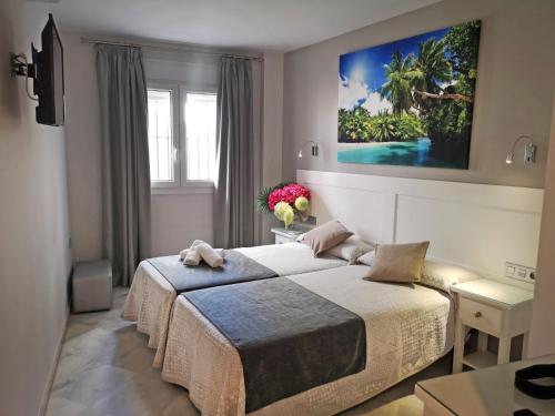 a bedroom with two beds and a painting on the wall at Hostal Bodega in Conil de la Frontera