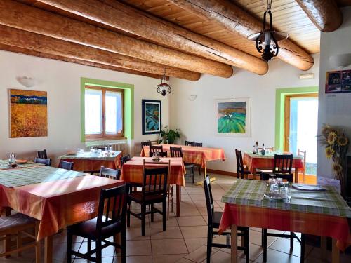 a restaurant with wooden ceilings and tables and chairs at Agriturismo Cavria in Castione Andevenno