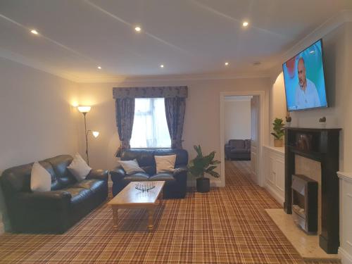 a living room with a couch and a tv at Valley Grove Bungalows in Saundersfoot