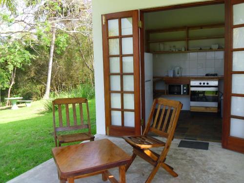 eine Terrasse mit 2 Stühlen, einem Tisch und einer Küche in der Unterkunft Bellevue Guest Lodge in Southbroom