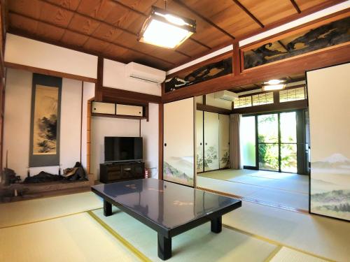 a room with a glass table in a room with paintings at Yadokari Kumano in Kumano