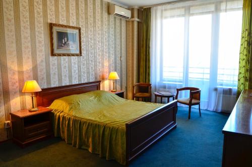 Habitación de hotel con cama, sillas y ventana en Diplomat ApartHotel, en Kiev