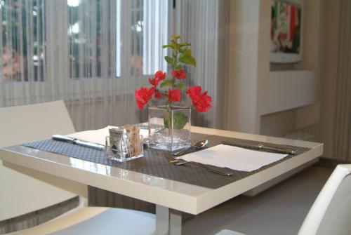 una mesa con un jarrón con flores rojas. en B&Beach Cagliari guest house, en Cagliari