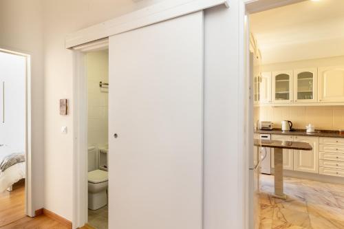 a white kitchen with a toilet and a table at White Apartment - T2 near Beach in São João do Estoril