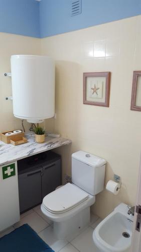 a bathroom with a white toilet and a sink at Vila Rosa Portimão in Portimão