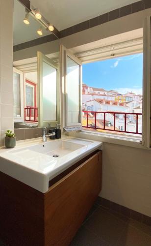 a bathroom with a large white sink and a window at Lucky Number 79 - UNESCO World Heritage Penthouse in Coimbra