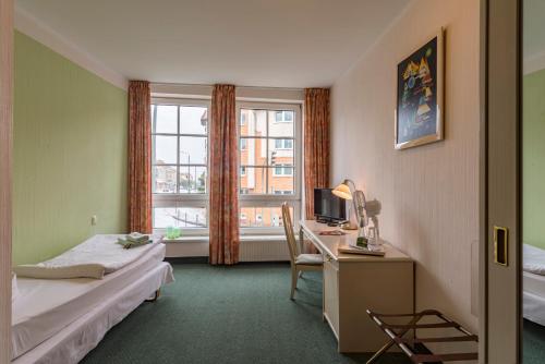 Zimmer mit 2 Betten, einem Schreibtisch und einem Fenster in der Unterkunft Hotel Overdiek in Prenzlau