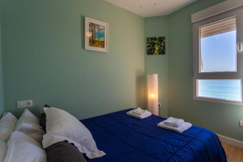 a bedroom with a blue bed and a window at GAVIOTA Family Home free parking by Cadiz4Rentals in Cádiz