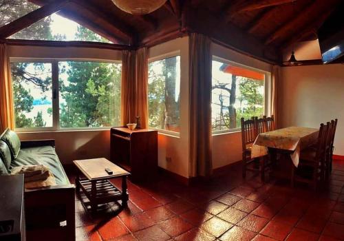 a living room with a table and some windows at Aucapillan in San Carlos de Bariloche