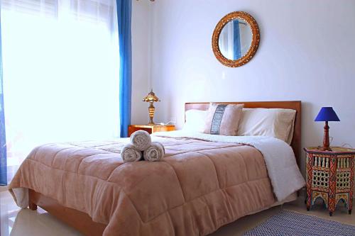 um quarto com uma cama grande e um espelho na parede em Hara Appart Luxe famille uniquement em Saïdia