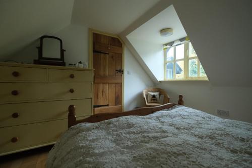 a bedroom with a bed and a dresser and a window at Chestnut Cottage in Eardisley