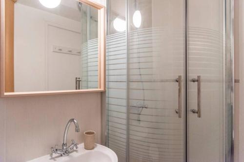 ein Bad mit einer Glasdusche und einem Waschbecken in der Unterkunft Appartement au calme + parking in Caen