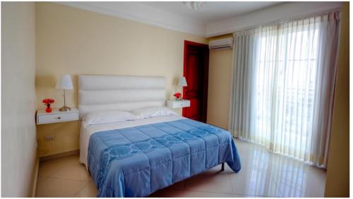 a bedroom with a large bed with a blue blanket at Hotel Shakey in Santo Domingo