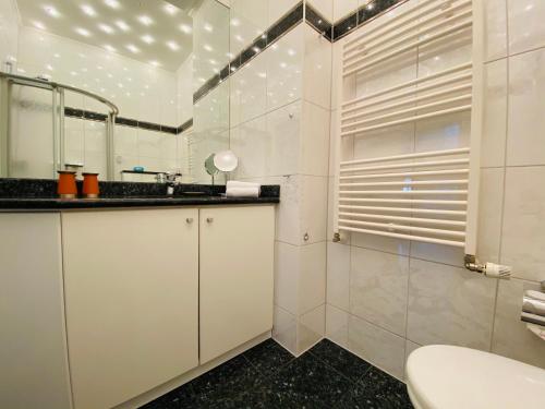 La salle de bains blanche est pourvue d'un lavabo et d'un miroir. dans l'établissement Residenz Bleichröder - Ferienwohnung Cäcilie, à Heringsdorf
