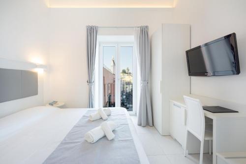 a white bedroom with a flat screen tv on the wall at Vento di mare in Procida