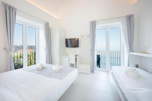 a white bedroom with two beds and a balcony at Vento di mare in Procida
