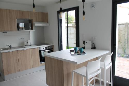 a kitchen with a white counter and wooden cabinets at MAGNIFIQUES APPTS à 1 MINUTE DE LA PLAGE in Andernos-les-Bains