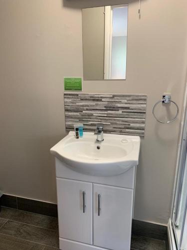 a bathroom with a white sink and a mirror at The Greenwich Rooms - Burger & Bird Bar & Restaurant in Peacehaven