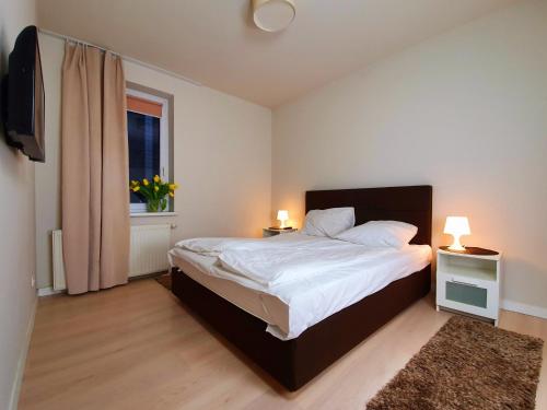a bedroom with a bed with two lamps and a window at Chopin Apartments - Eco in Warsaw