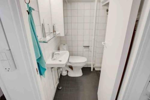 La salle de bains blanche est pourvue de toilettes et d'un lavabo. dans l'établissement The heart of Copenhagen-Queen's Neighbor, à Copenhague